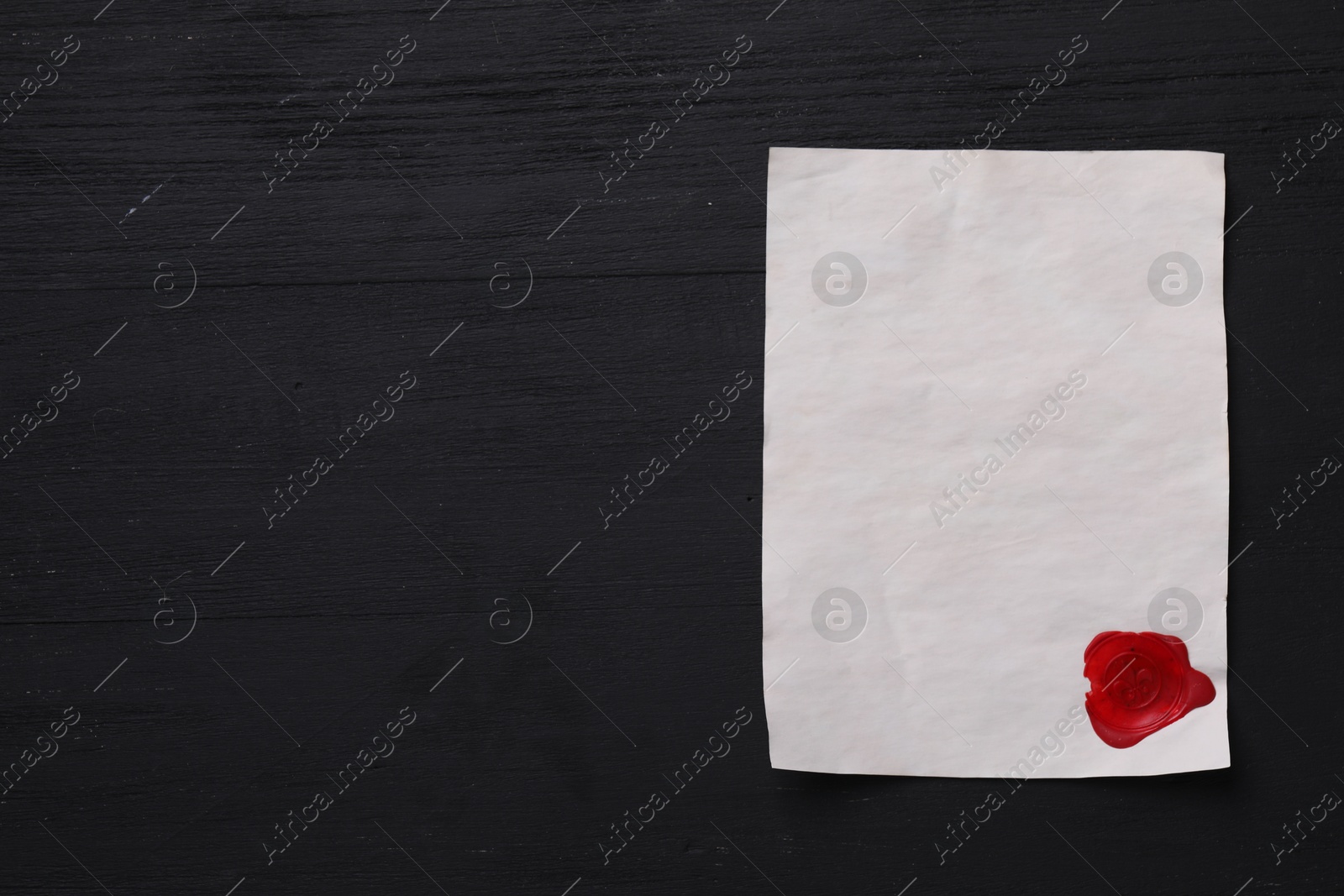 Photo of Blank old letter with wax stamp on black wooden table, top view. Space for text