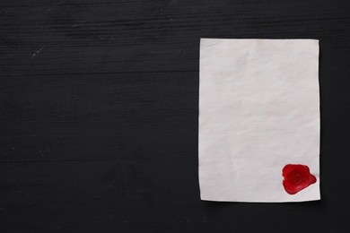 Blank old letter with wax stamp on black wooden table, top view. Space for text