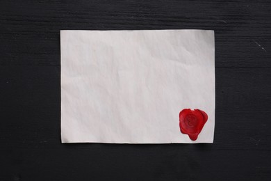 Photo of Blank old letter with wax stamp on black wooden table, top view