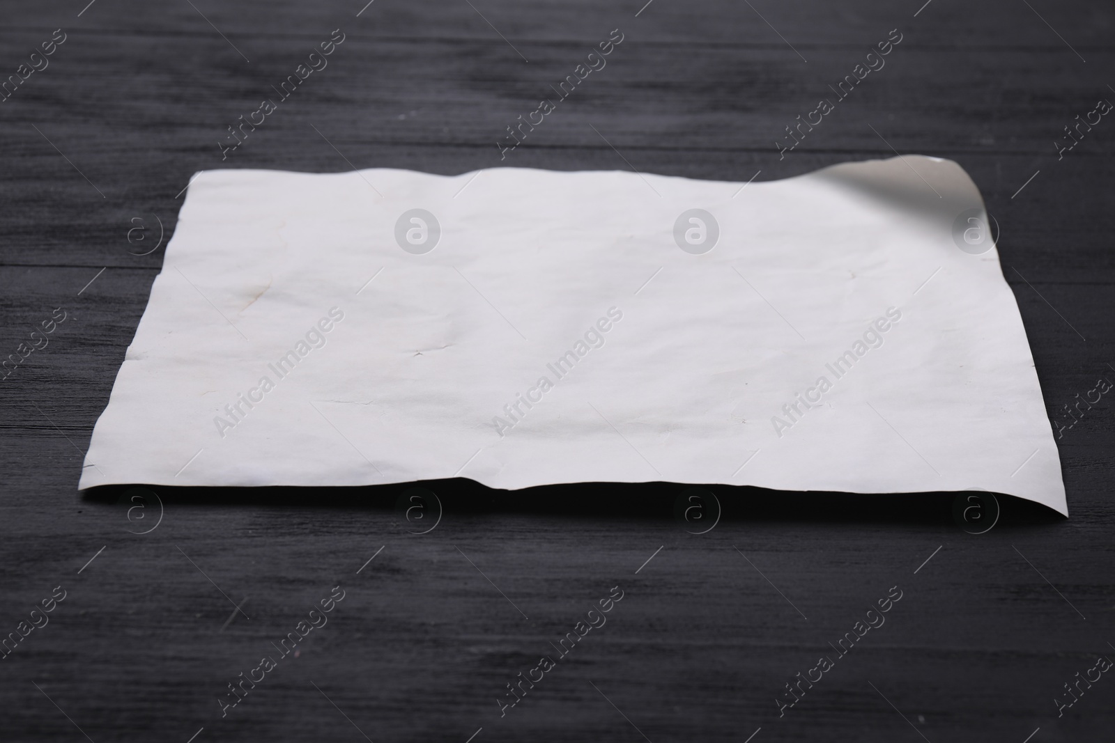 Photo of Blank old letter on black wooden table, closeup