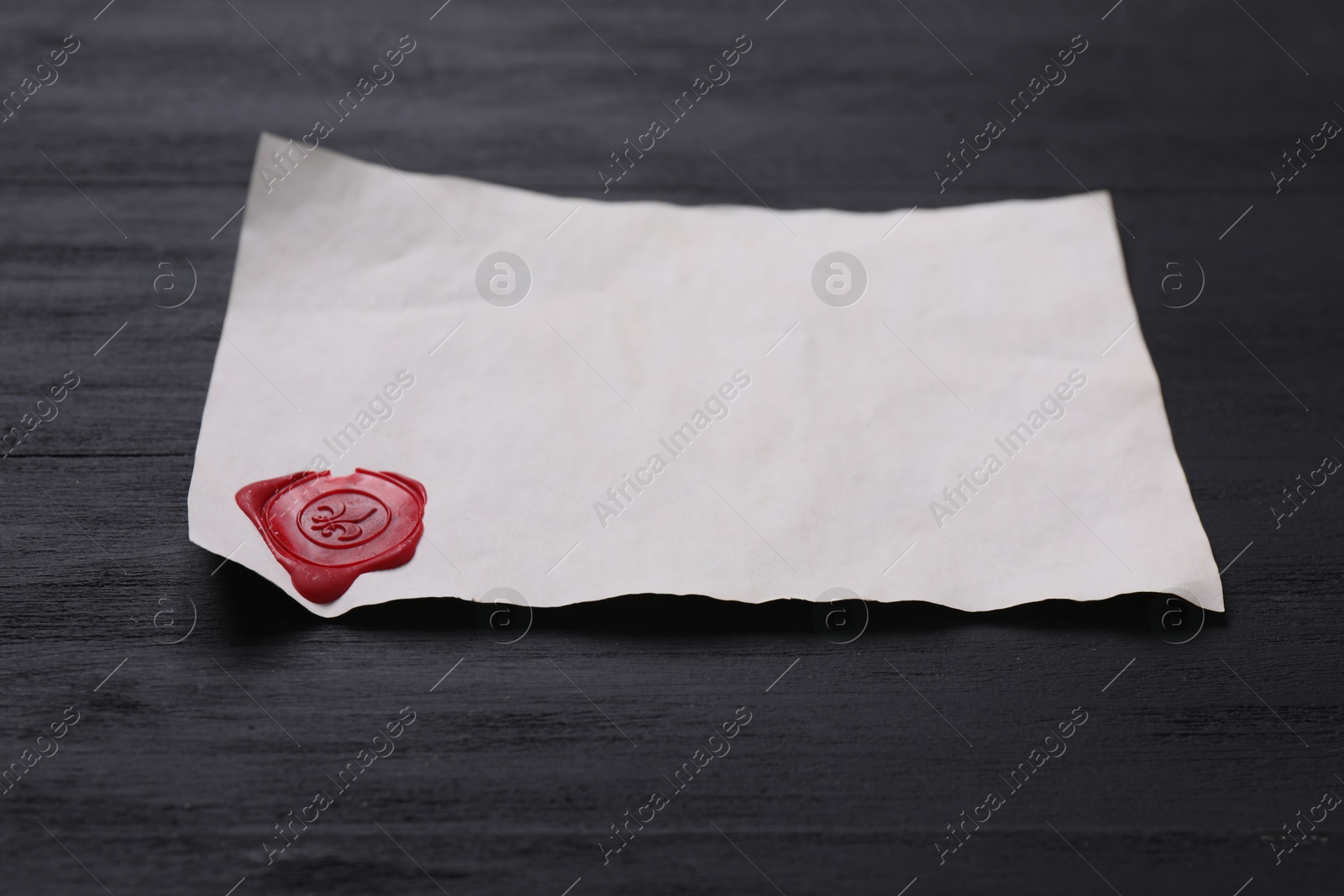 Photo of Old letter with wax stamp on black wooden table, closeup