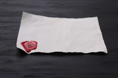 Old letter with wax stamp on black wooden table, closeup