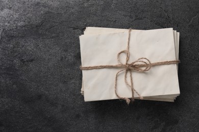 Stack of old letters tied with twine on grey table, top view. Space for text