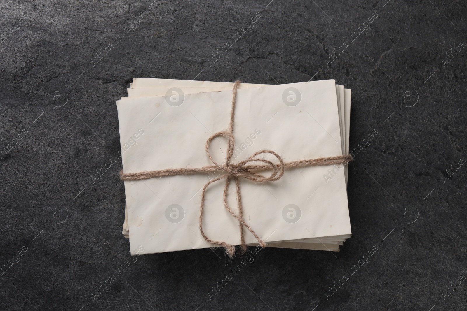 Photo of Stack of old letters tied with twine on grey table, top view