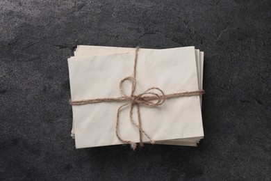 Stack of old letters tied with twine on grey table, top view