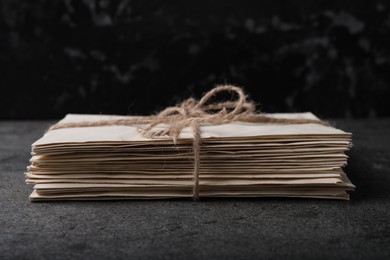 Photo of Stack of old letters tied with twine on grey table, closeup