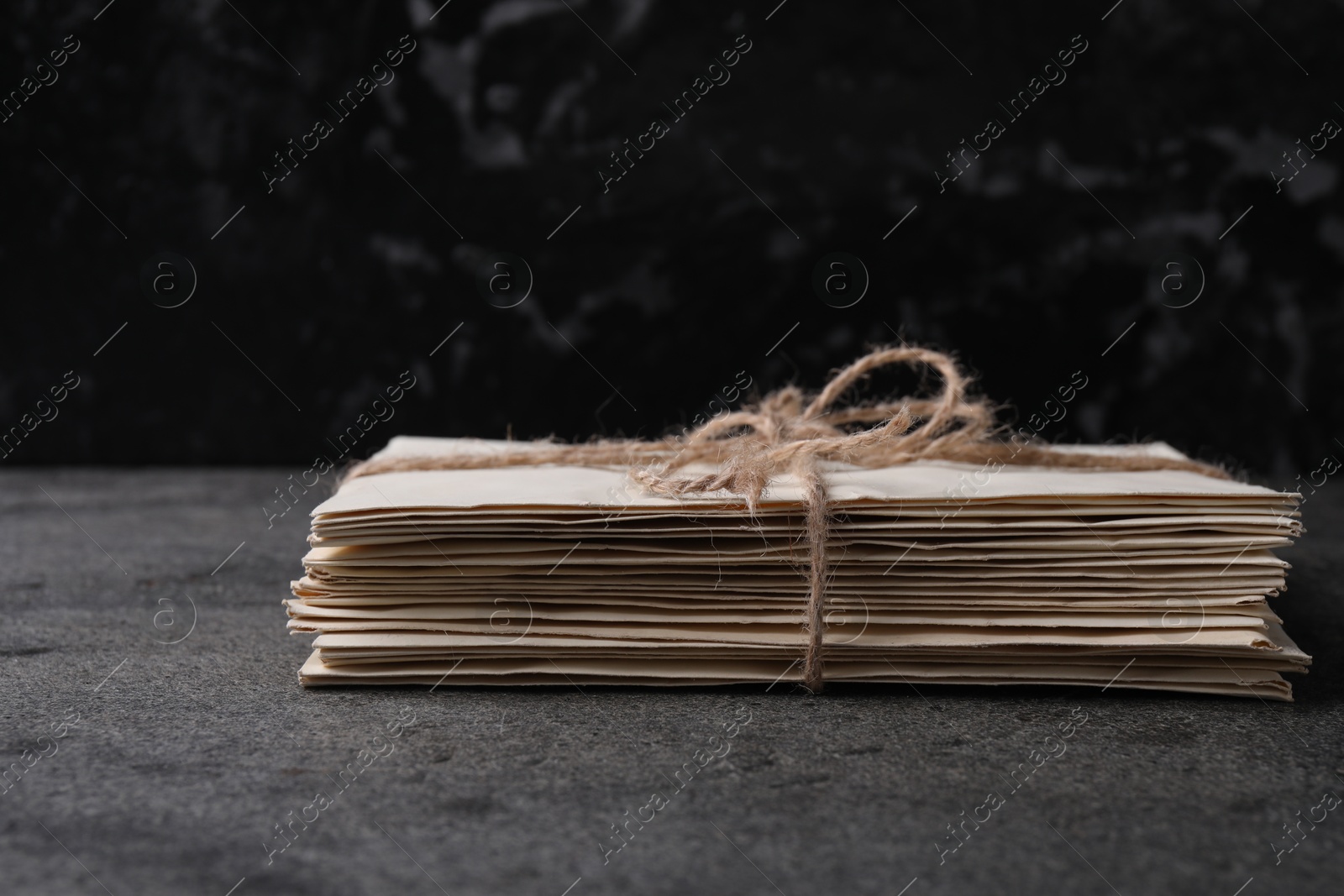 Photo of Stack of old letters tied with twine on grey table, closeup