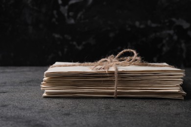 Stack of old letters tied with twine on grey table, closeup