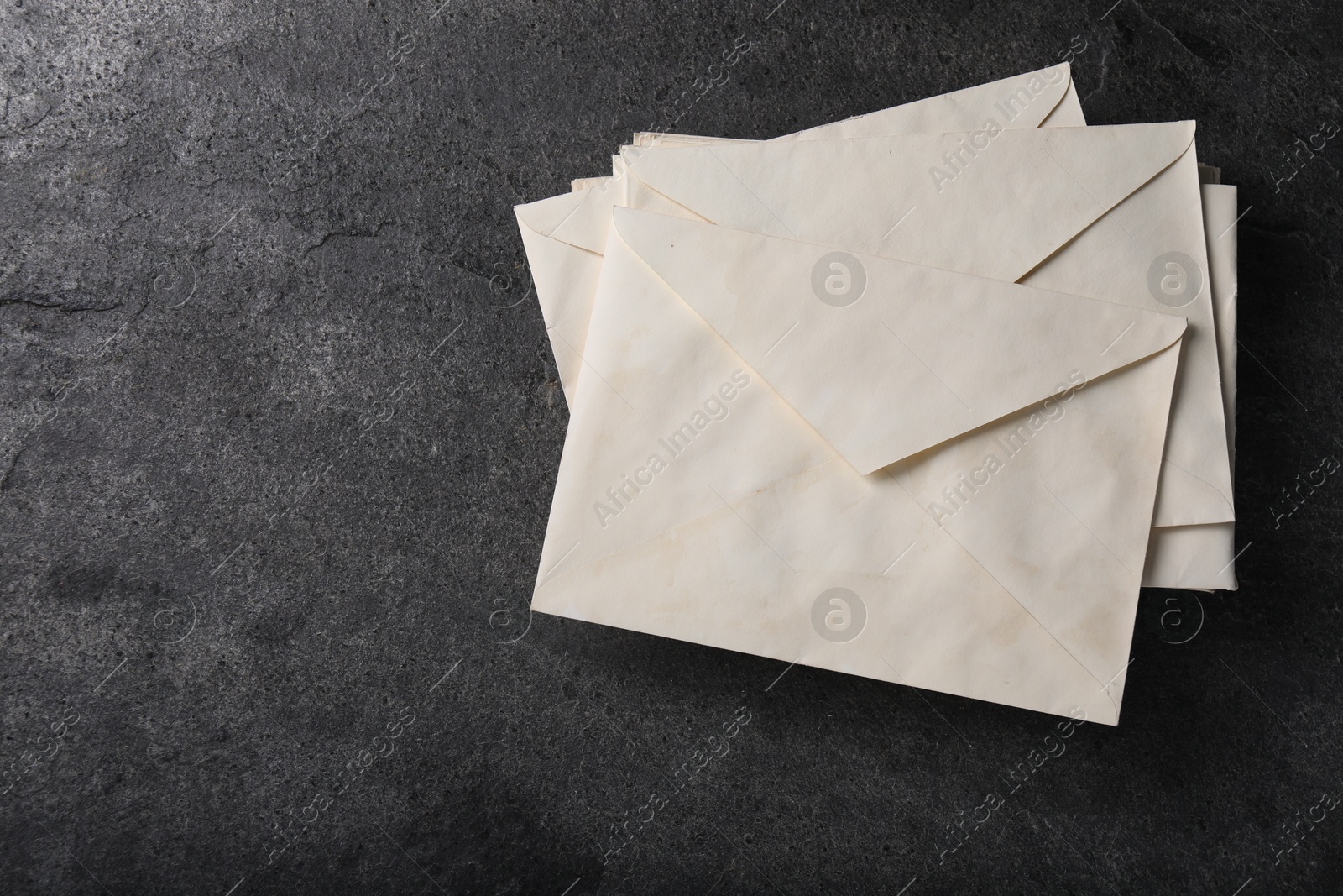 Photo of Old letter envelopes on grey table, top view. Space for text