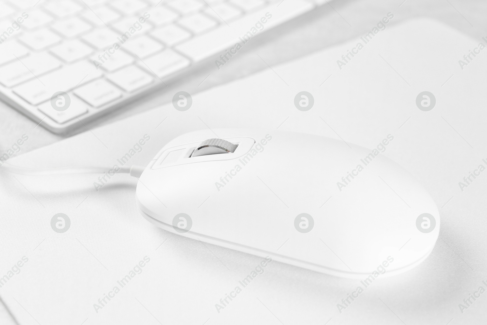 Photo of Computer mouse with mousepad and keyboard on light table, closeup