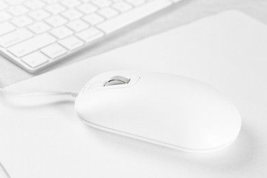 Photo of Computer mouse with mousepad and keyboard on light table, closeup