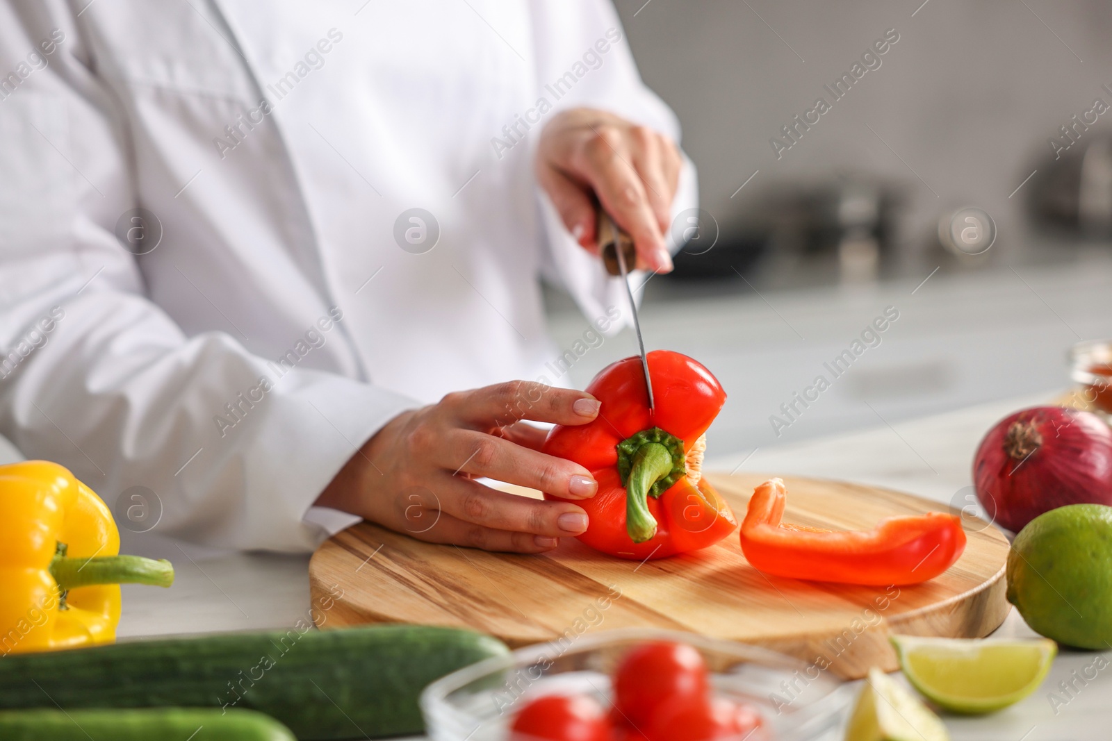 Photo of Professional chef cutting pepper at table in kitchen, closeup