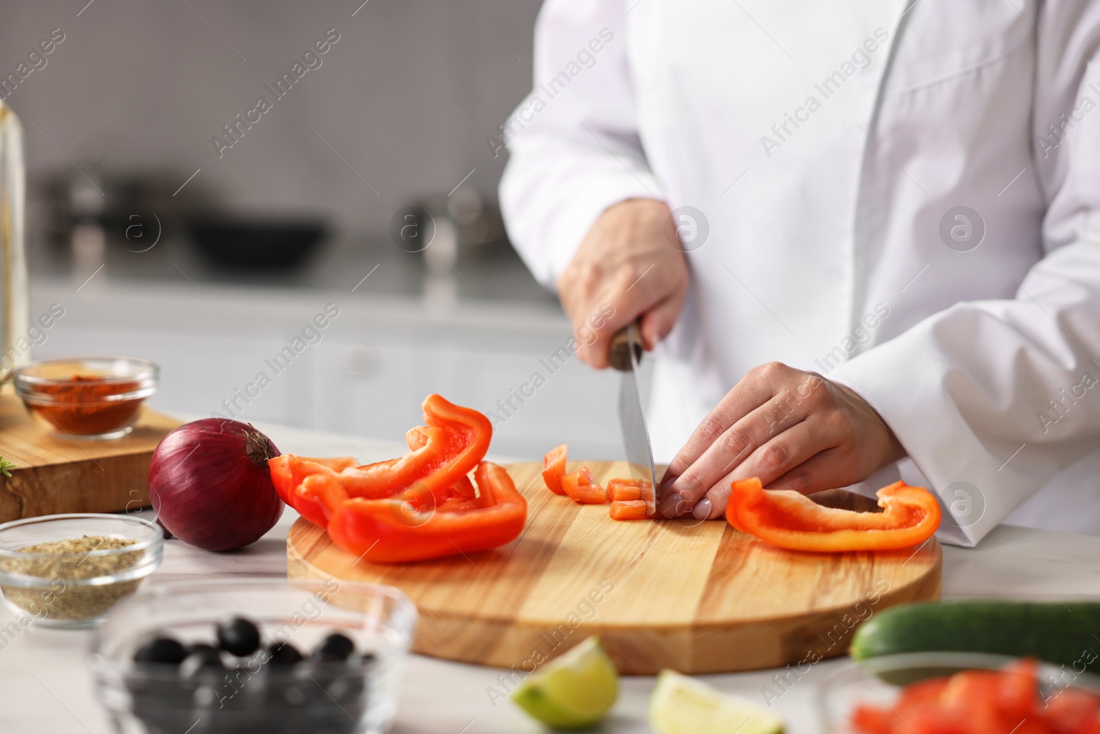 Photo of Professional chef cutting pepper at table in kitchen, closeup