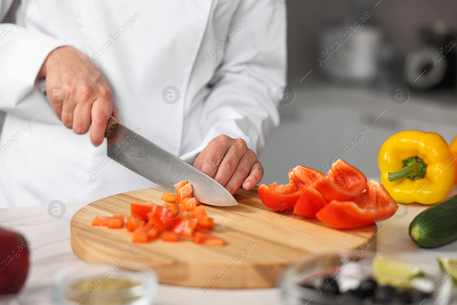 Photo of Professional chef cutting pepper at table in kitchen, closeup