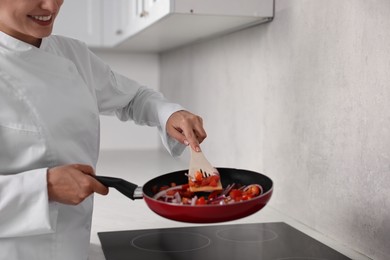 Professional chef cooking delicious food on stove in kitchen, closeup