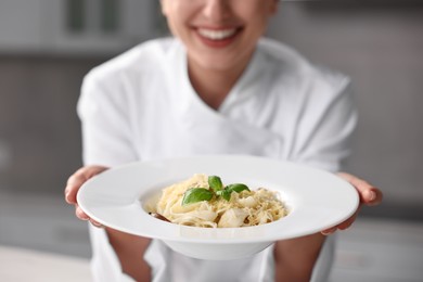 Professional chef with delicious pasta in kitchen, closeup