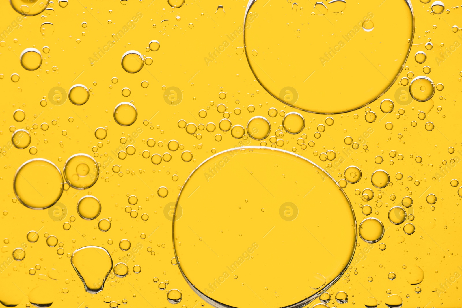 Photo of Sample of cosmetic oil on yellow background, macro view