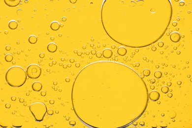 Sample of cosmetic oil on yellow background, macro view