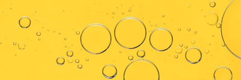 Photo of Sample of cosmetic oil on yellow background, macro view