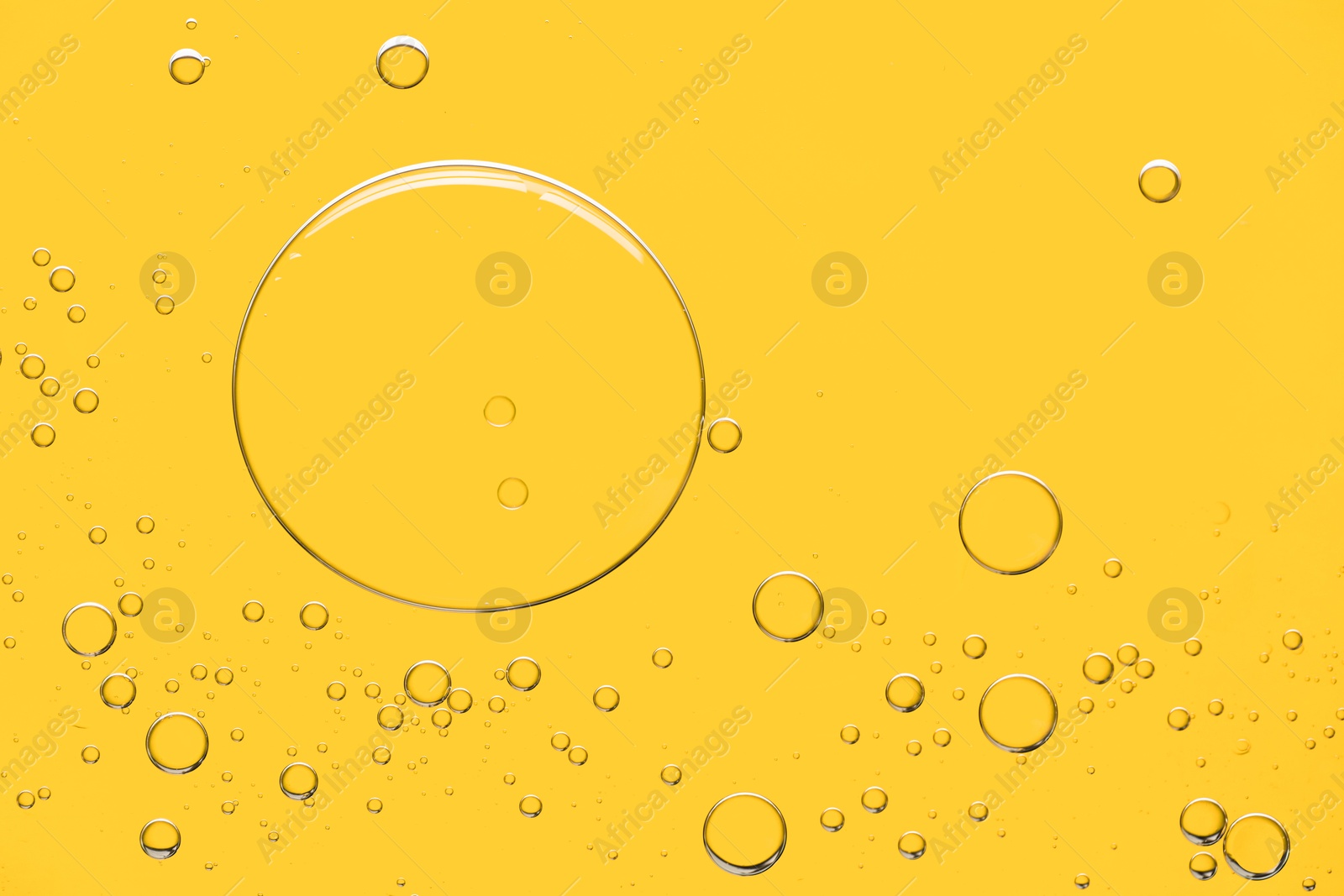 Photo of Sample of cosmetic oil on yellow background, macro view