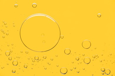 Photo of Sample of cosmetic oil on yellow background, macro view