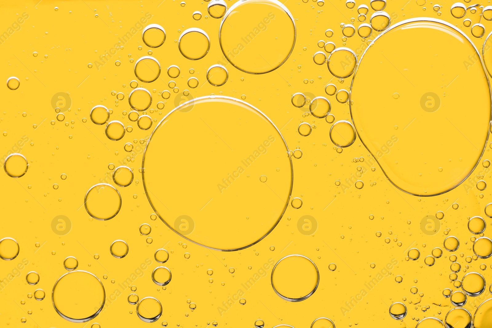 Photo of Sample of cosmetic oil on yellow background, macro view