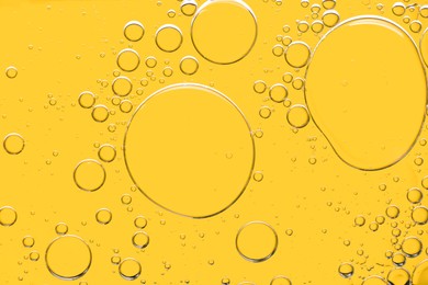 Photo of Sample of cosmetic oil on yellow background, macro view