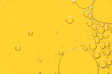 Sample of cosmetic oil on yellow background, macro view