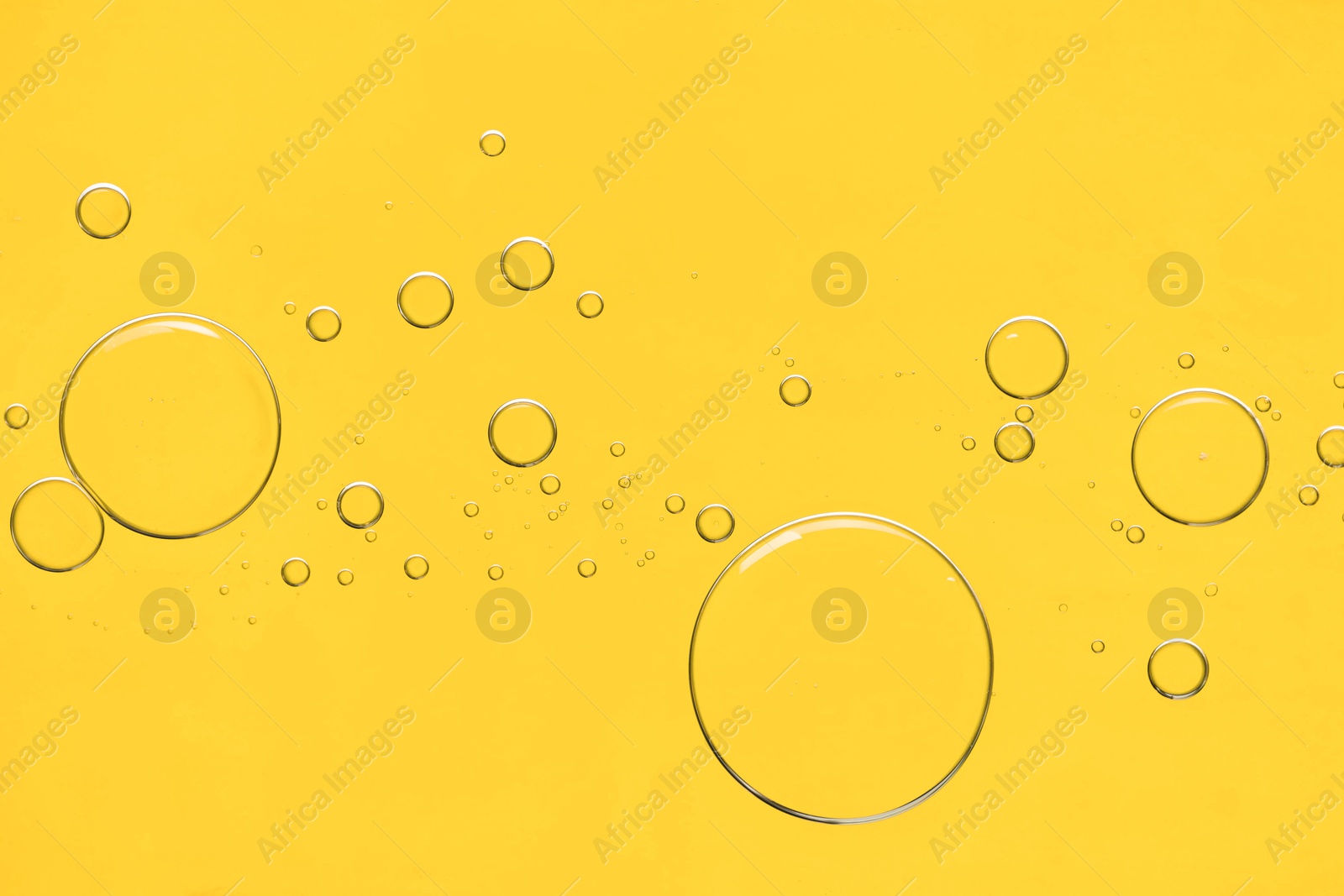 Photo of Sample of cosmetic oil on yellow background, macro view