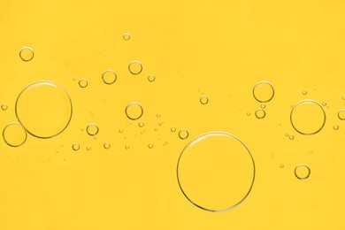 Photo of Sample of cosmetic oil on yellow background, macro view