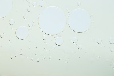 Sample of cosmetic oil on light grey background, macro view