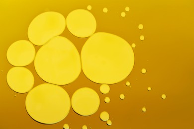 Sample of cosmetic oil on dark yellow background, macro view