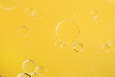 Photo of Sample of cosmetic oil on yellow background, macro view