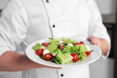 Photo of Professional chef with delicious salad in kitchen, closeup