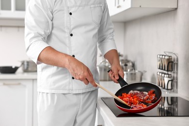 Photo of Professional chef cooking delicious food on stove in kitchen, closeup