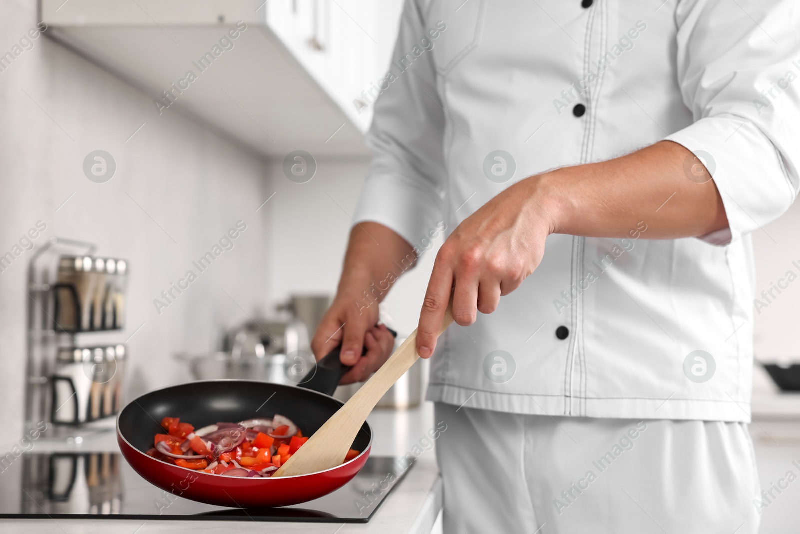 Photo of Professional chef cooking delicious food on stove in kitchen, closeup