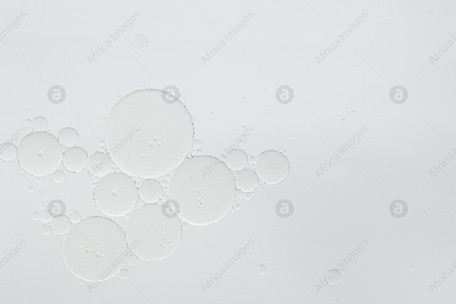 Photo of Cosmetic oil bubbles on white background, macro view. Space for text