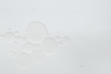 Cosmetic oil bubbles on white background, macro view. Space for text