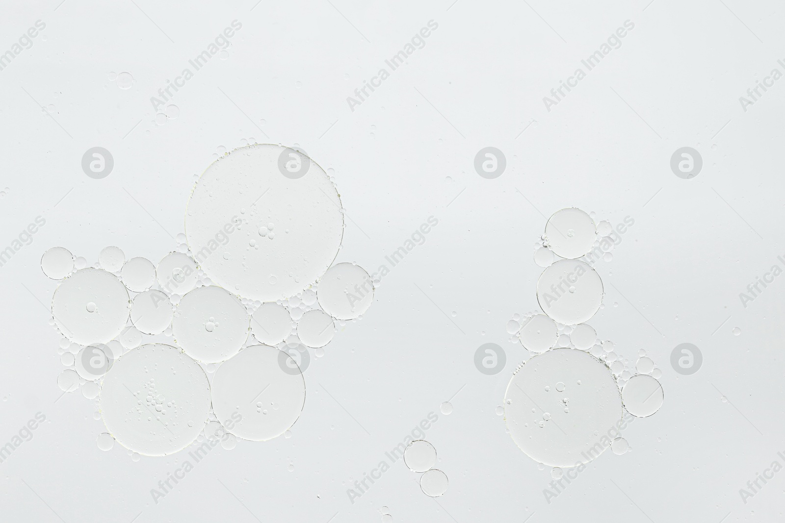 Photo of Essential oil bubbles on white background, macro view. Cosmetic product