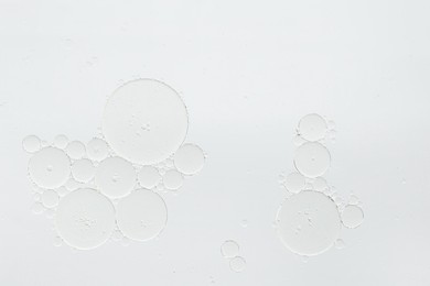 Photo of Essential oil bubbles on white background, macro view. Cosmetic product