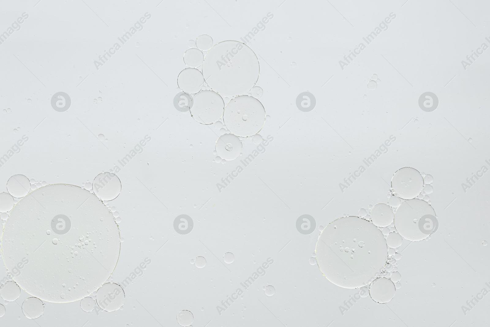 Photo of Essential oil bubbles on white background, macro view. Cosmetic product