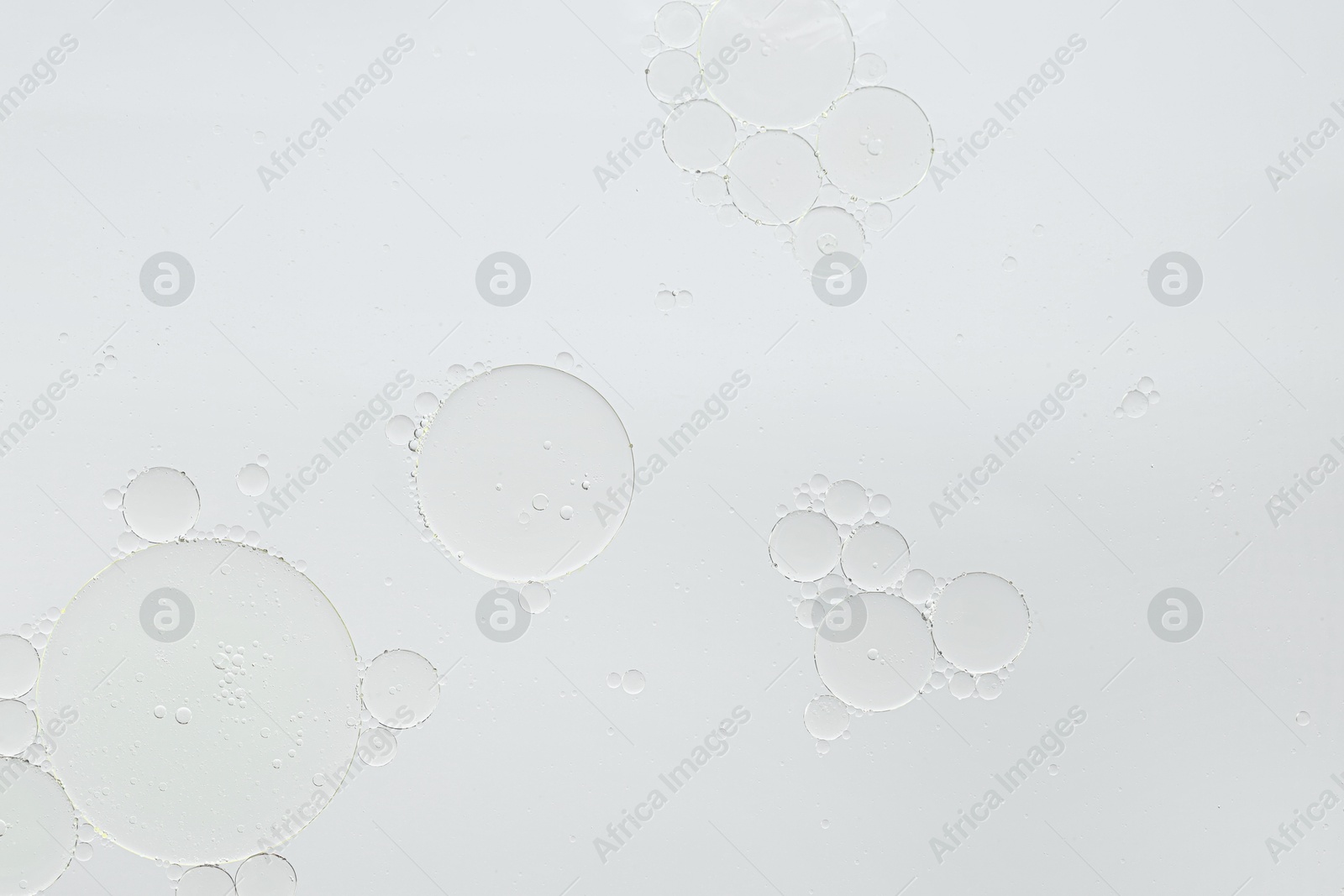 Photo of Essential oil bubbles on white background, macro view. Cosmetic product