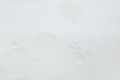 Photo of Essential oil bubbles on white background, macro view. Cosmetic product