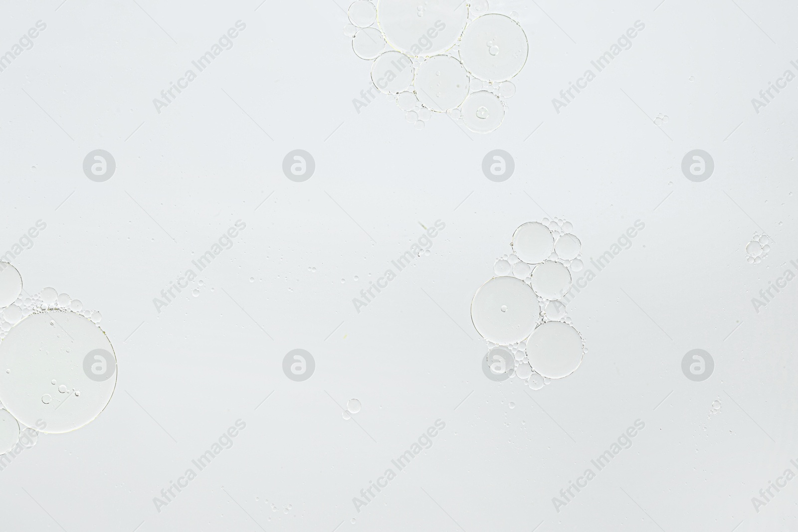 Photo of Essential oil bubbles on white background, macro view. Cosmetic product