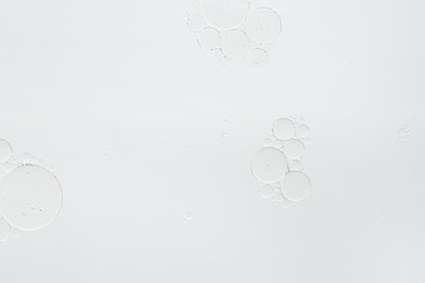 Photo of Essential oil bubbles on white background, macro view. Cosmetic product