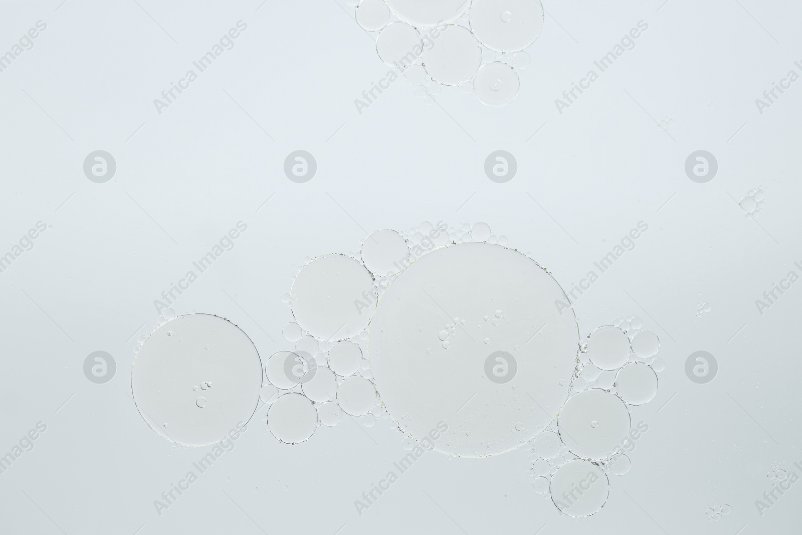 Photo of Essential oil bubbles on white background, macro view. Cosmetic product