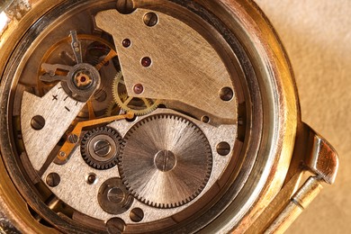 Mechanism of vintage wrist watch on beige background, top view