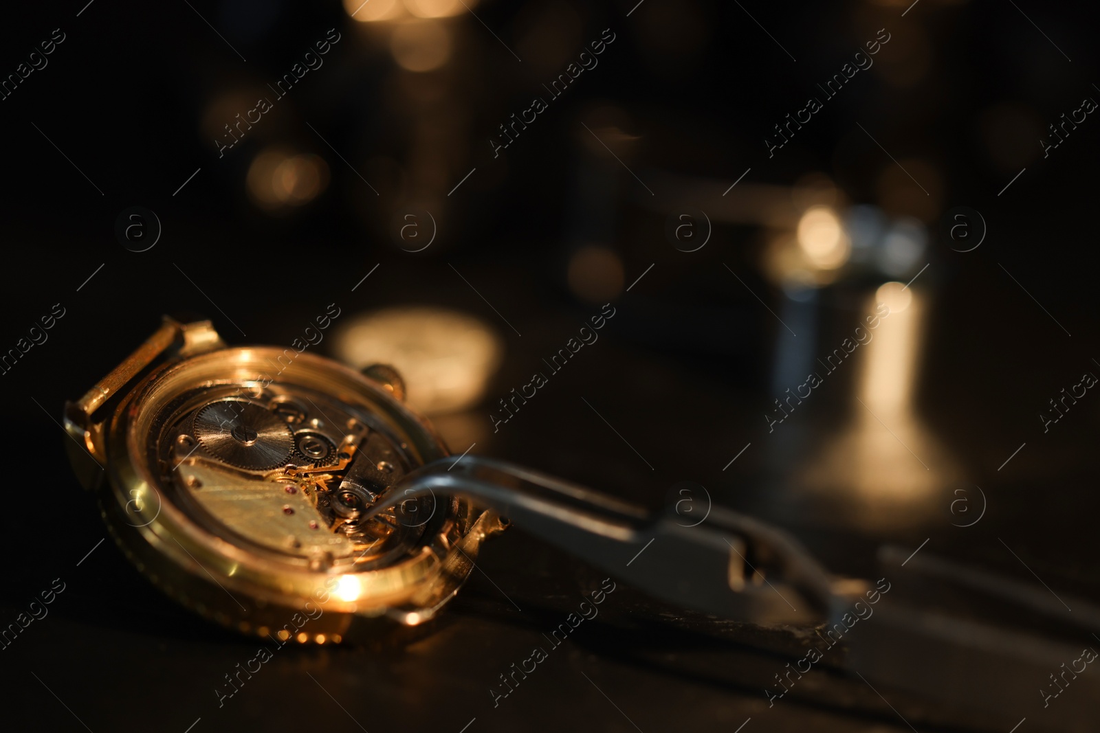 Photo of Mechanism of vintage wrist watch and tool on black table, closeup