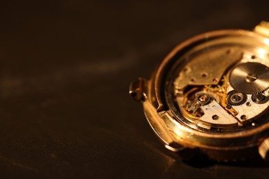 Photo of Mechanism of vintage wrist watch on black background, closeup. Space for text