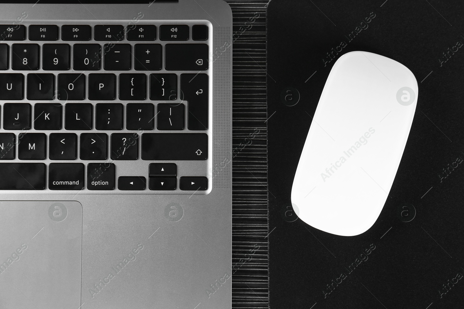 Photo of White computer mouse with mousepad and laptop on black wooden table, flat lay